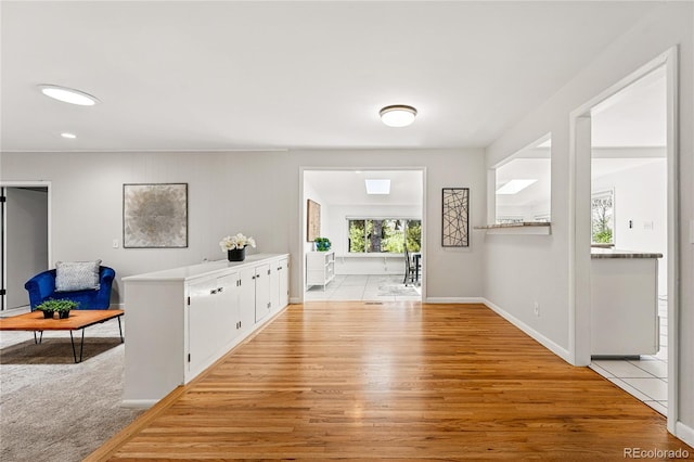 corridor with light wood-style floors, baseboards, and recessed lighting