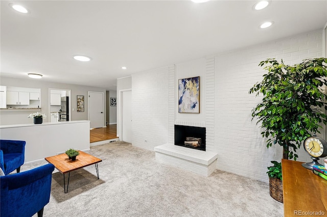 living area featuring brick wall, light colored carpet, a fireplace, and recessed lighting