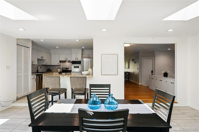 dining space featuring a skylight, recessed lighting, and light tile patterned floors