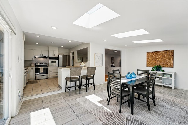 dining space featuring a skylight, light tile patterned flooring, recessed lighting, and baseboards
