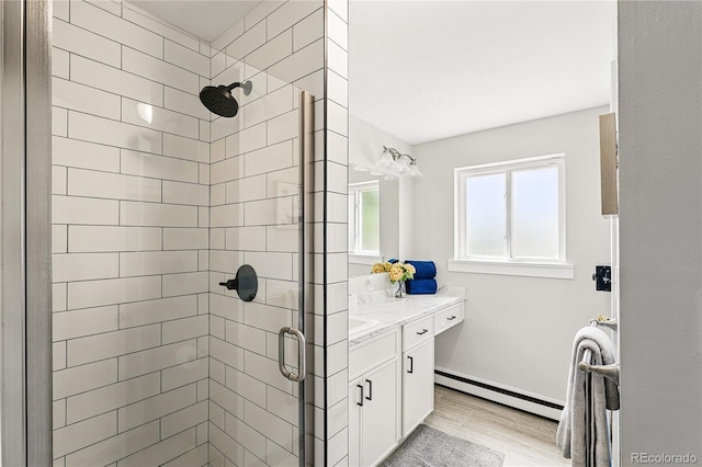 bathroom featuring baseboard heating, a shower stall, vanity, and wood finished floors