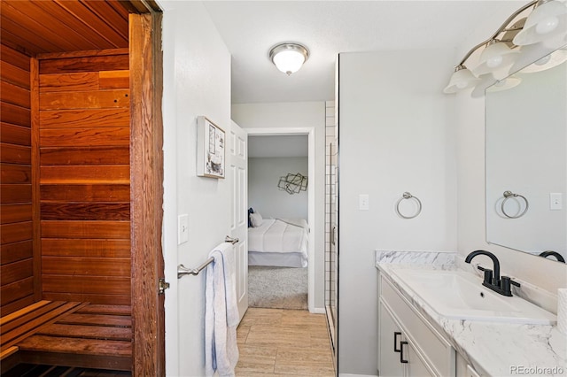 bathroom with wood finished floors, vanity, connected bathroom, and baseboards