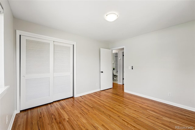 unfurnished bedroom with a closet, light wood-type flooring, and baseboards