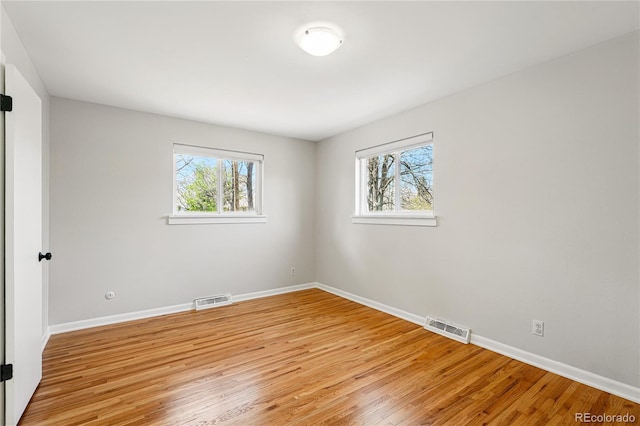 empty room featuring plenty of natural light, light wood-style floors, and baseboards