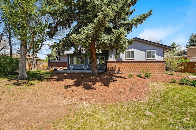 back of property with brick siding, board and batten siding, and a patio