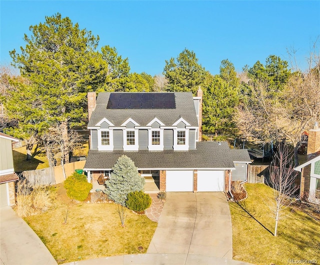 view of front of house featuring brick siding, a front lawn, fence, concrete driveway, and a chimney