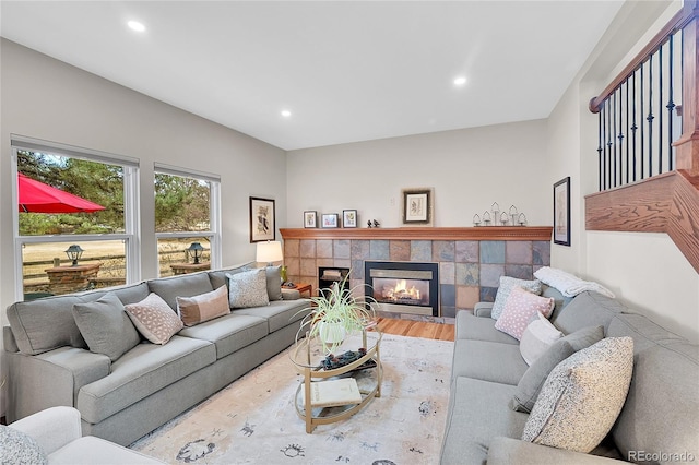 living area with recessed lighting, a tile fireplace, and wood finished floors