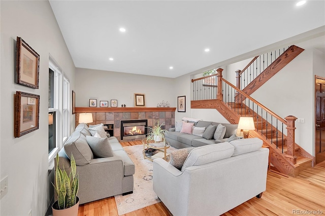 living room with stairway, recessed lighting, light wood-style floors, and a tile fireplace