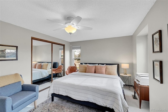 bedroom featuring a closet, light carpet, a textured ceiling, and a ceiling fan