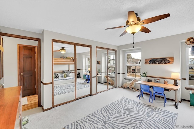 carpeted office featuring baseboards, a textured ceiling, and a ceiling fan