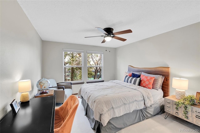 bedroom featuring a textured ceiling, a ceiling fan, and light carpet