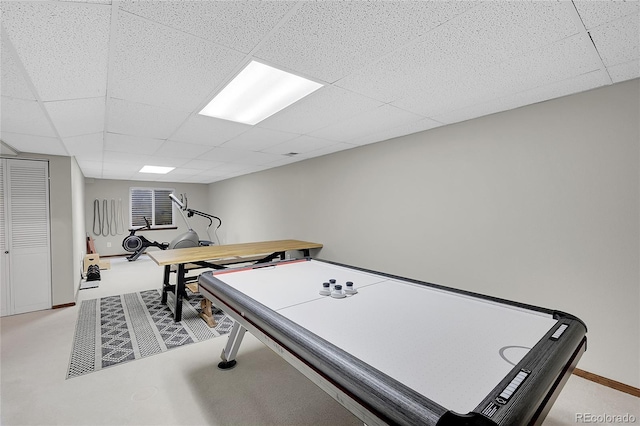 game room featuring a drop ceiling, baseboards, and light colored carpet