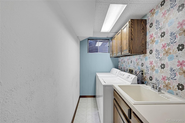 washroom featuring a sink, baseboards, cabinet space, and washing machine and dryer