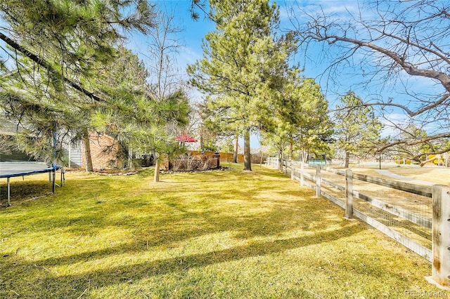 view of yard featuring a trampoline and fence