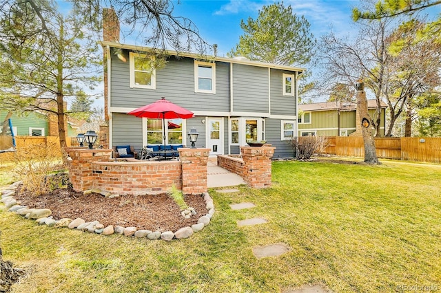 rear view of house featuring a yard, a patio area, a chimney, and fence