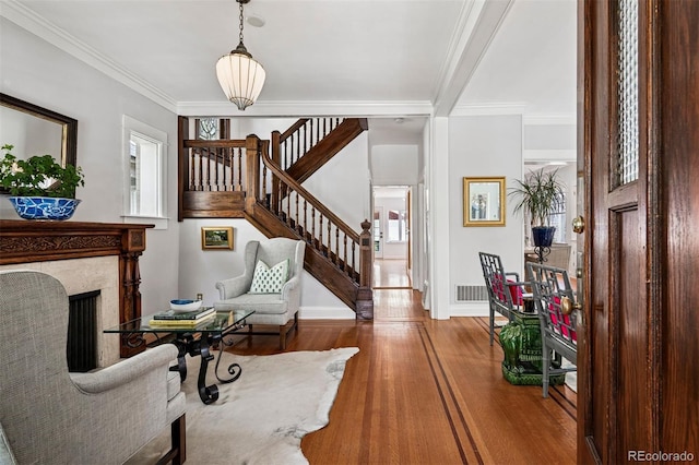 living area featuring stairs, wood finished floors, ornamental molding, baseboards, and a premium fireplace