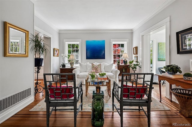 living area featuring wood finished floors, crown molding, and baseboards