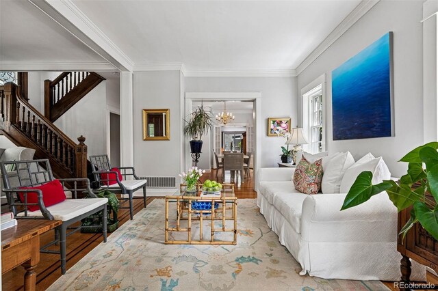 living room with a chandelier, wood finished floors, ornamental molding, and stairway
