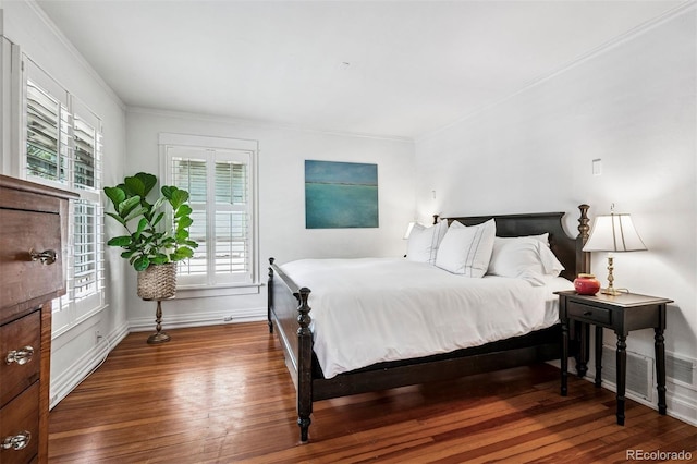 bedroom featuring wood finished floors, crown molding, and baseboards
