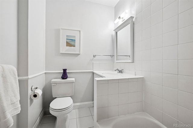 full bath featuring toilet, tile patterned flooring, baseboards, a tub to relax in, and vanity