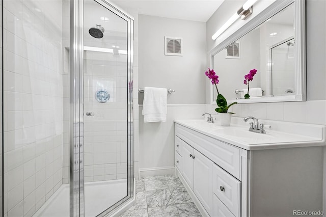 full bath featuring a stall shower, marble look tile flooring, and double vanity