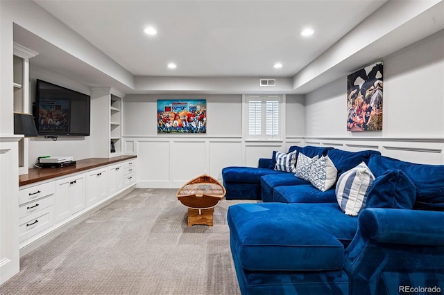 living area with light carpet, a decorative wall, recessed lighting, and a wainscoted wall