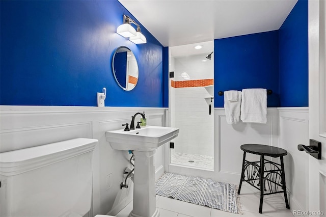 full bathroom with tile patterned flooring, wainscoting, a tile shower, a decorative wall, and recessed lighting