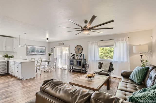 living area with ceiling fan, light wood-type flooring, and plenty of natural light