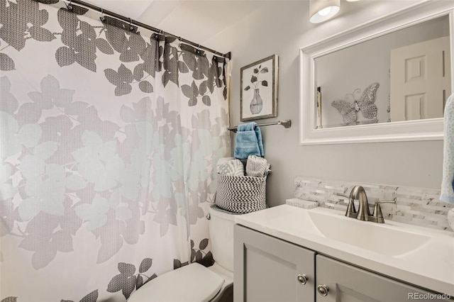 bathroom featuring tasteful backsplash, vanity, and toilet