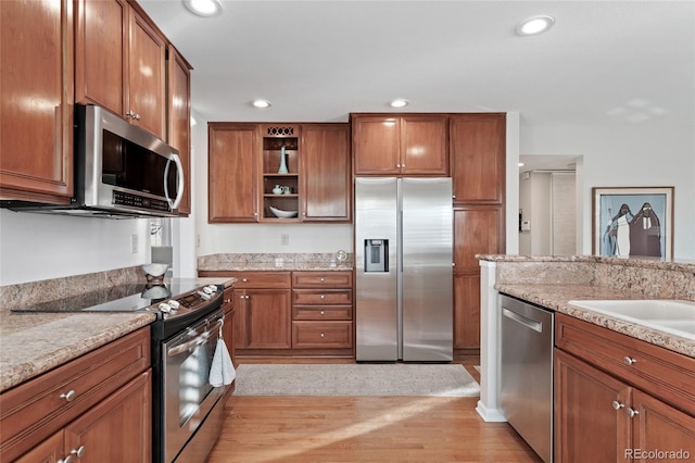 kitchen with stainless steel appliances, brown cabinetry, open shelves, and recessed lighting