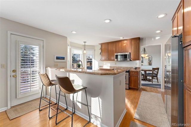 kitchen featuring appliances with stainless steel finishes, brown cabinetry, a sink, and a kitchen breakfast bar