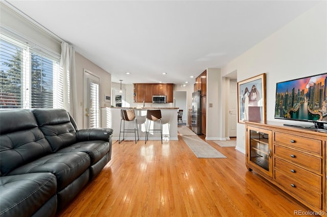 living area with light wood-style floors, baseboards, and recessed lighting