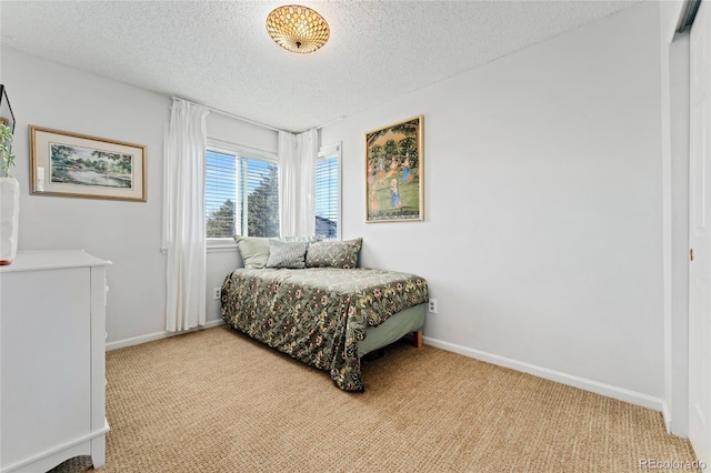 bedroom featuring light carpet, baseboards, and a textured ceiling