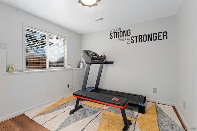 workout area with wood finished floors, visible vents, and baseboards