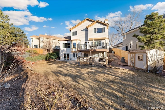 back of property featuring an outbuilding, a chimney, a storage unit, fence, and a wooden deck