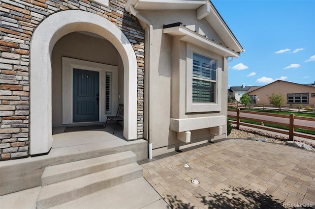 property entrance with stucco siding and stone siding