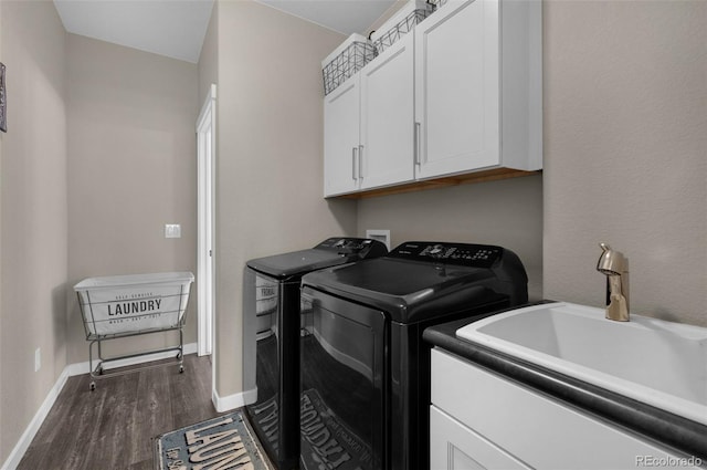 laundry room featuring washing machine and clothes dryer, cabinet space, a sink, baseboards, and dark wood-style floors