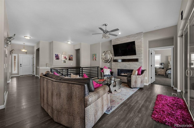 living room featuring ceiling fan, a fireplace, and dark wood-type flooring