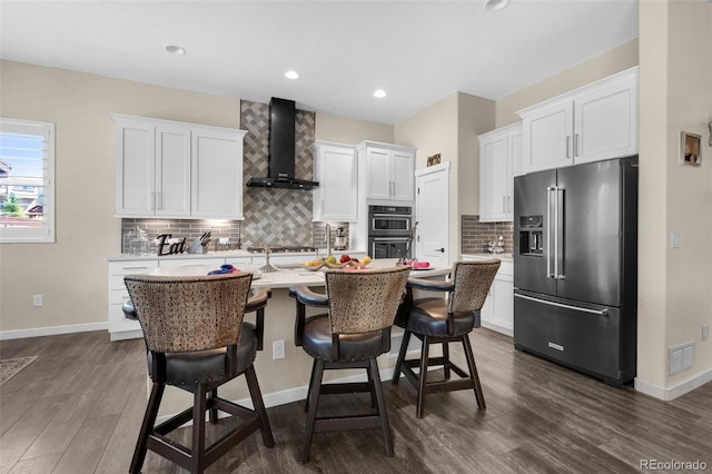 kitchen featuring dark wood-style flooring, visible vents, high end refrigerator, light countertops, and wall chimney exhaust hood