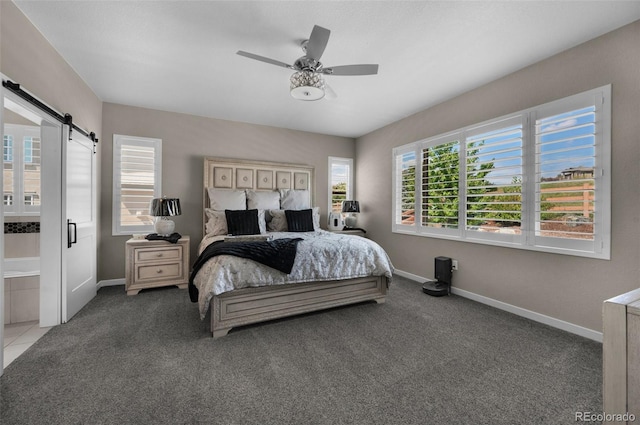 carpeted bedroom with ceiling fan, ensuite bathroom, and a barn door