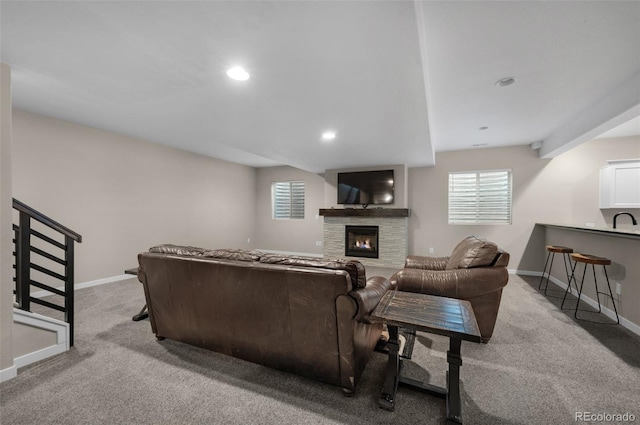 living area with carpet flooring, recessed lighting, baseboards, and a stone fireplace