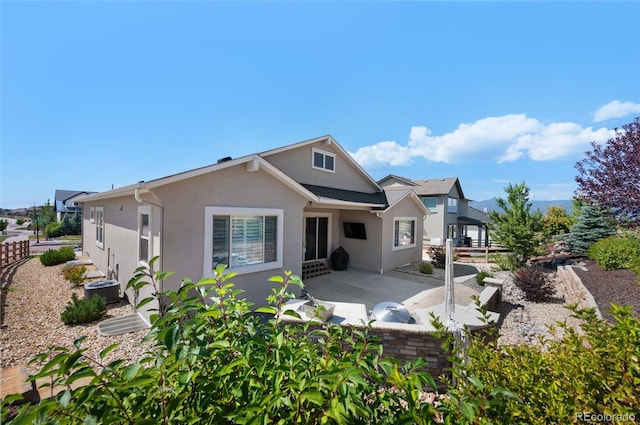 back of property with fence, stucco siding, and a patio area