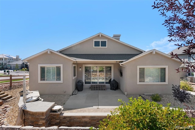 rear view of property featuring a patio, roof with shingles, and stucco siding
