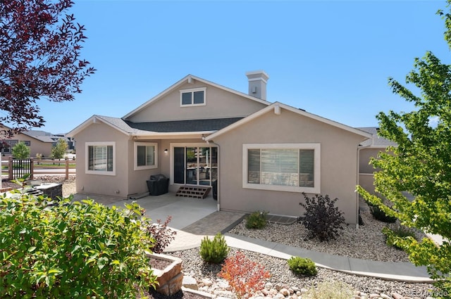 back of house featuring fence, a chimney, a patio area, and stucco siding