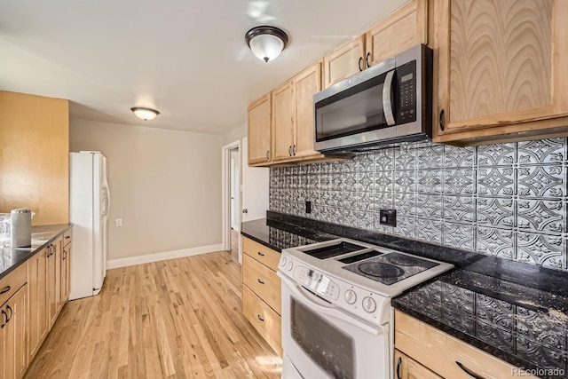 kitchen featuring tasteful backsplash, dark stone countertops, white appliances, light brown cabinetry, and light wood-type flooring