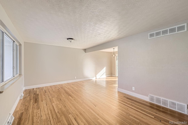 empty room featuring light wood-type flooring and a textured ceiling