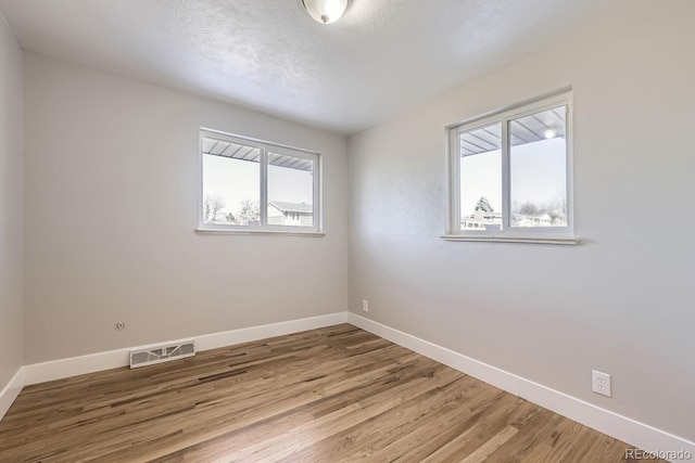 spare room featuring hardwood / wood-style floors, a textured ceiling, and a wealth of natural light