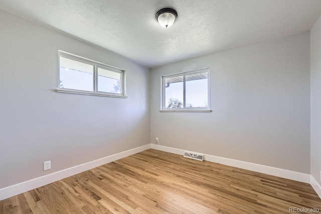 unfurnished room featuring a textured ceiling and light wood-type flooring