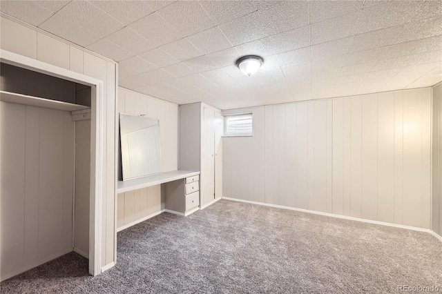 unfurnished bedroom with carpet, a closet, and wooden walls