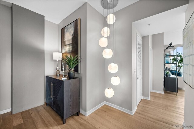 hallway featuring light wood finished floors and baseboards